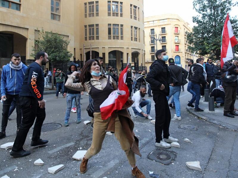 A Lebanese demonstrator hurls rocks over a fortified gate
