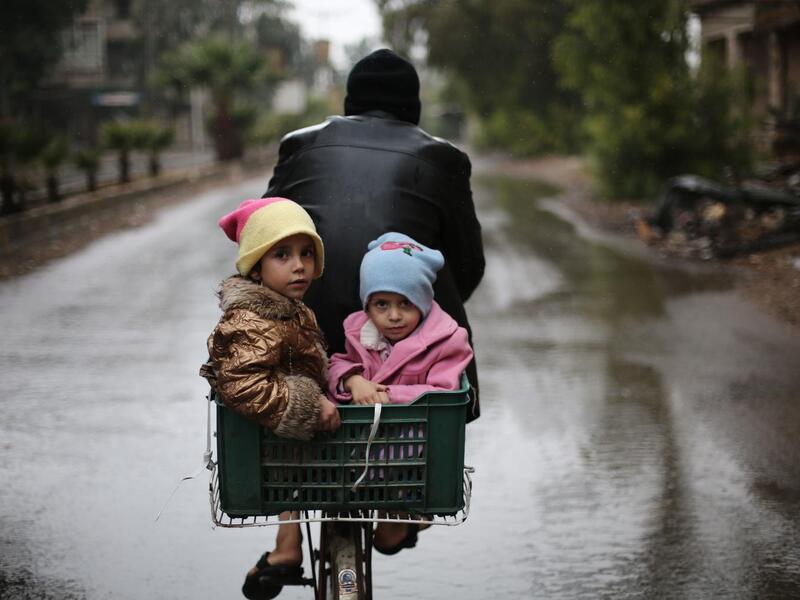 On 9 October in East Ghouta, children ride on the back of a bicycle.
