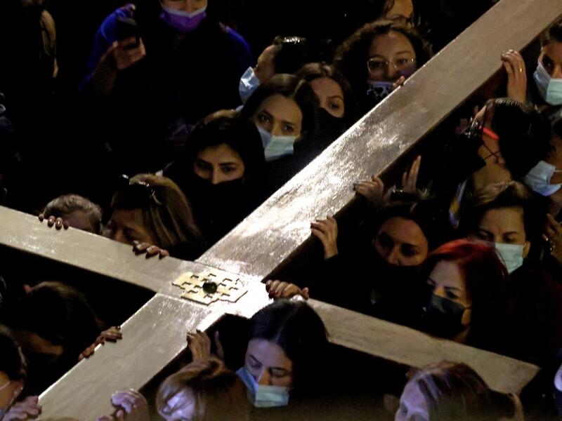 Christian worshippers carrying a wooden cross walk inside the Church of the Holy Sepulchre,