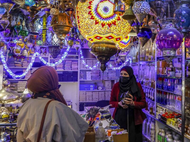 Women talk to a Palestinian shopkeeper selling Ramadan lanterns 