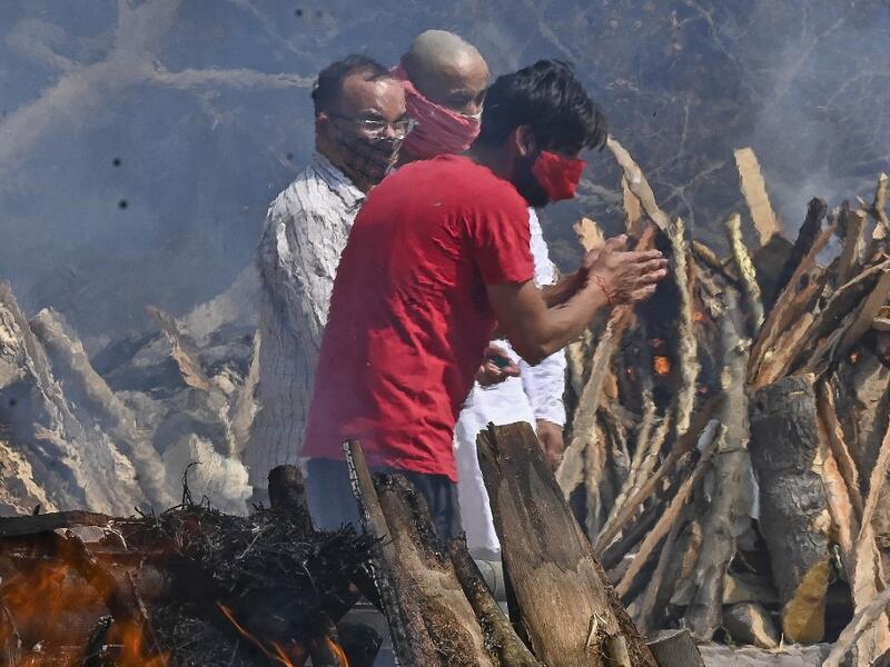 A man reacts as he performs the last rites of his relative amid the funeral pyres of victims who died of the Covid-19 coronavirus during mass cremation held at a crematorium in New Delhi 