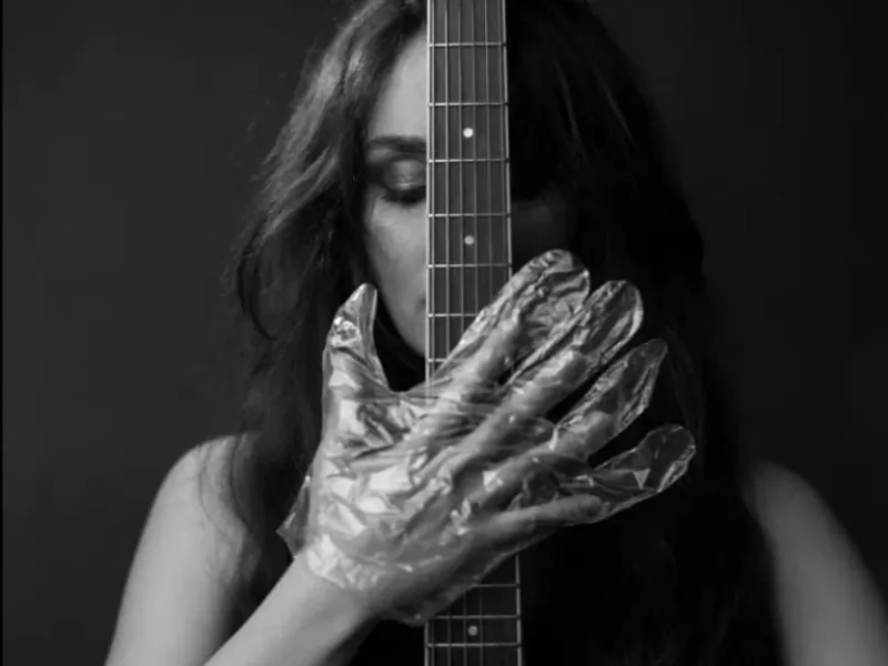The musician in foil gloves is holding the instrument
