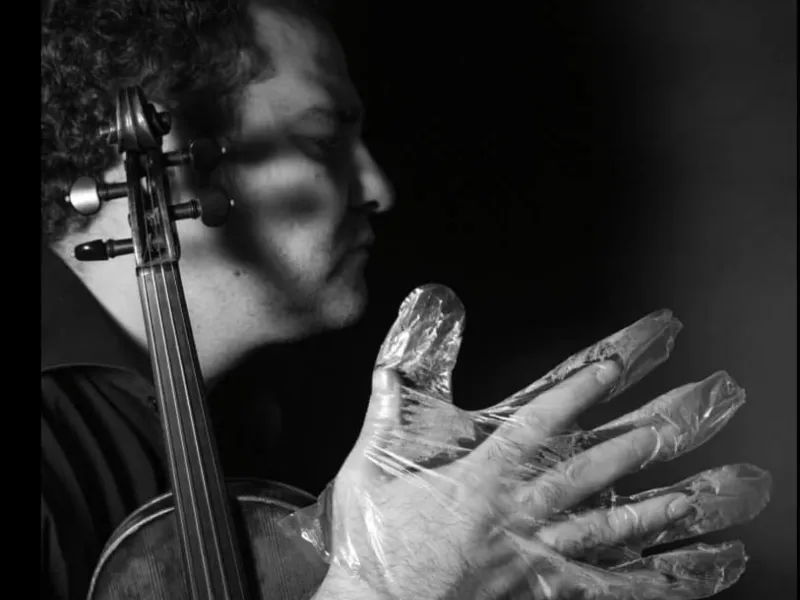 A musician in foil gloves is playing an instrument
