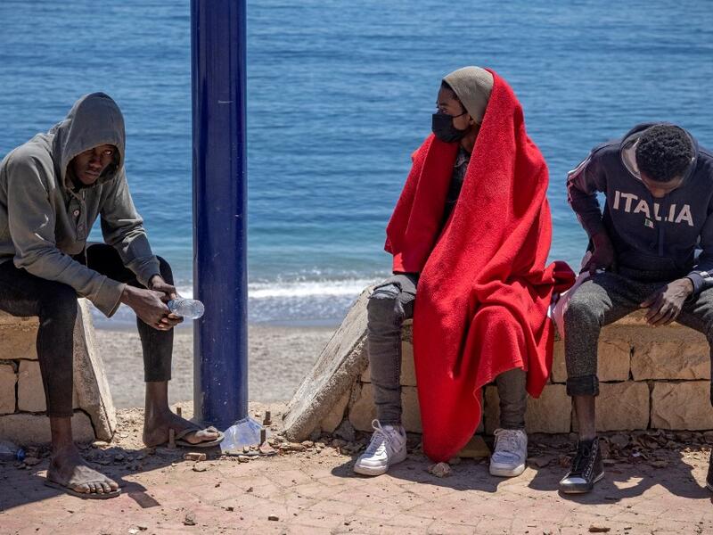 Subsaharian migants sit on a sea wall in the northern town of Fnideq as they attempt to cross the border from Morocco to Spain's North African enclave of Ceuta on May 19, 2021. Spain stepped up diplomatic pressure on Rabat as its prime minister flew into Ceuta, vowing to "restore order" in the North African enclave after a record 8,000 migrants reached its beaches from Morocco