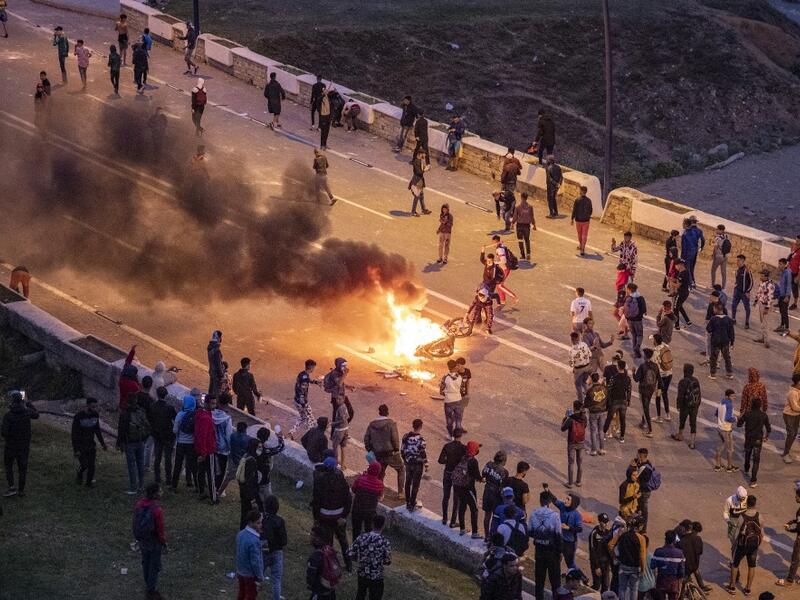 Migrants burn a motorbike as they clash with Moroccan riot police