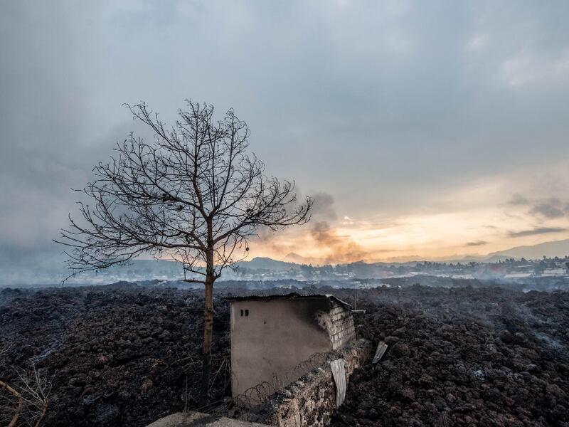 This general view shows a structure still standing, surrounded by the lava who flew during yesterday's eruption on May 23, 2021. A river of boiling lava came to a halt on the outskirts of Goma Sunday, sparing the city in eastern DR Congo from disaster after the nighttime eruption of Mount Nyiragongo sent thousands of terrified residents fleeing in panic. Fire and strong fumes emanated from the blackish molten rock as it swallowed up houses, heading towards Goma airport on the shores of Lake Kivu