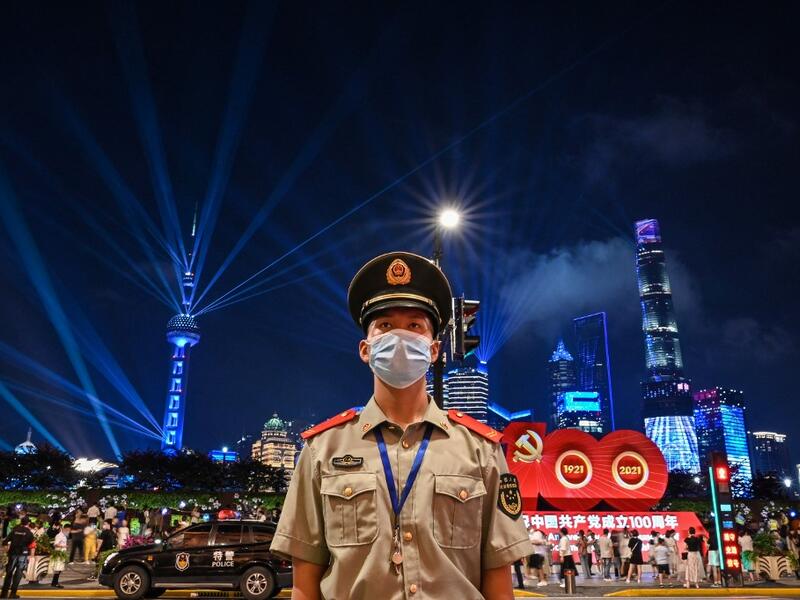 A Chinese paramilitary police stands guard while a light show is seen from the Bund in Shanghai on June 30, 2021, on the eve of the 100th anniversary of the Chinese Communist Party. 