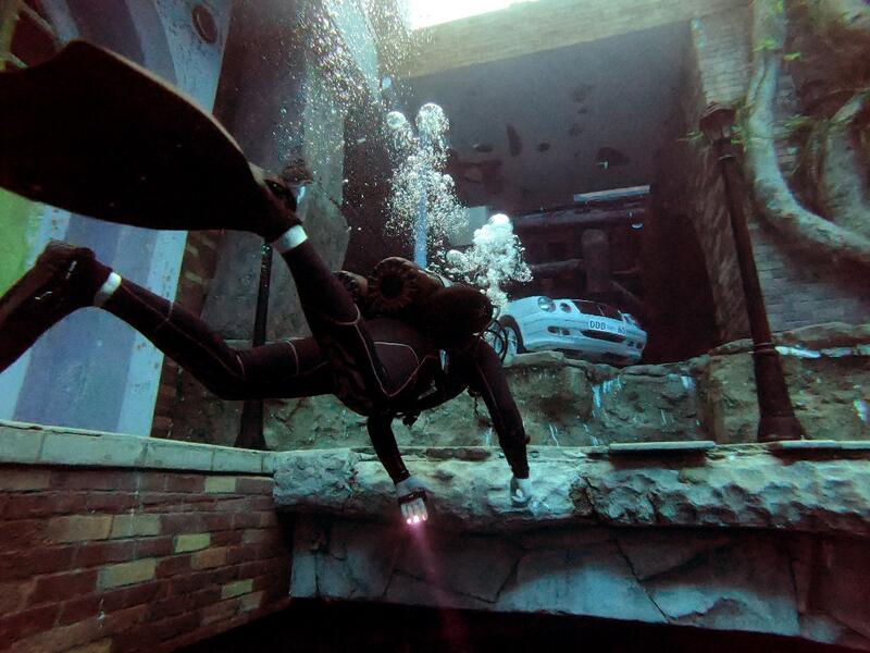 A diver explores a mock sunken city as he experiences Deep Dive Dubai, the deepest swimming pool in the world reaching 60m, in the United Arab Emirates, on July 10, 2021. The city of superlatives, with the world's tallest tower among its many records, Dubai now has the deepest swimming pool on the planet complete with a "sunken city" for divers to explore. GIUSEPPE CACACE / AFP