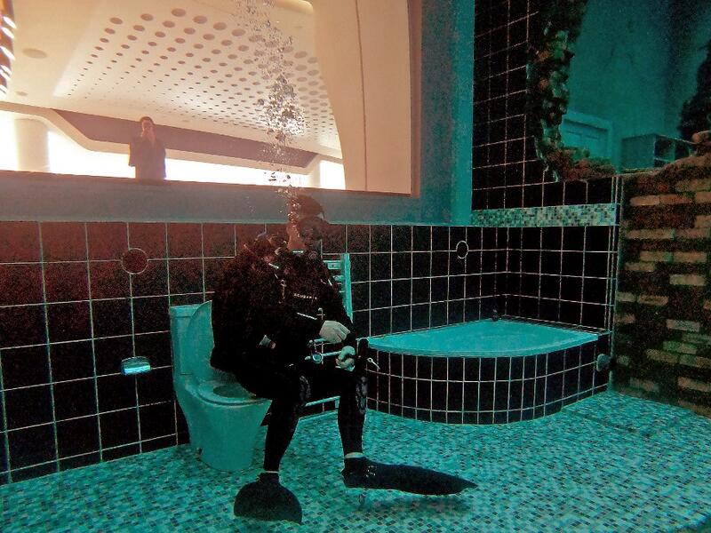 A diver explores a mock sunken city as he experiences Deep Dive Dubai, the deepest swimming pool in the world reaching 60m, in the United Arab Emirates, on July 10, 2021. The city of superlatives, with the world's tallest tower among its many records, Dubai now has the deepest swimming pool on the planet complete with a "sunken city" for divers to explore. GIUSEPPE CACACE / AFP