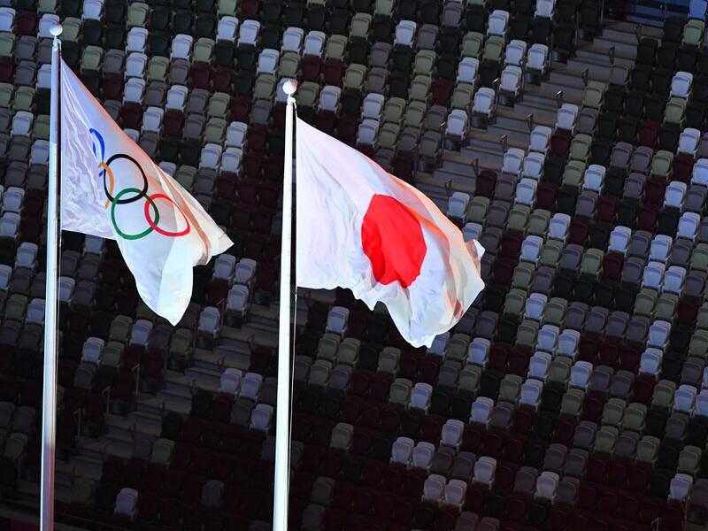 An overview shows the Olympic (L) and Japan's national flag fluttering with empty stands seen in the background during the opening ceremony of the Tokyo 2020 Olympic Games, at the Olympic Stadium, in Tokyo