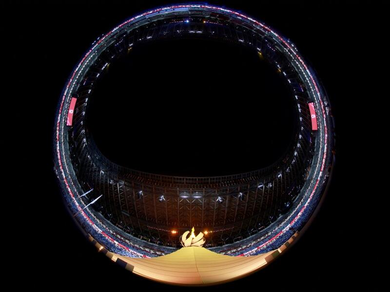 This picture taken with a fish-eye lens shows the Olympic cauldron and flame during the opening ceremony of the Tokyo 2020 Olympic Games, at the Olympic Stadium, in Tokyo