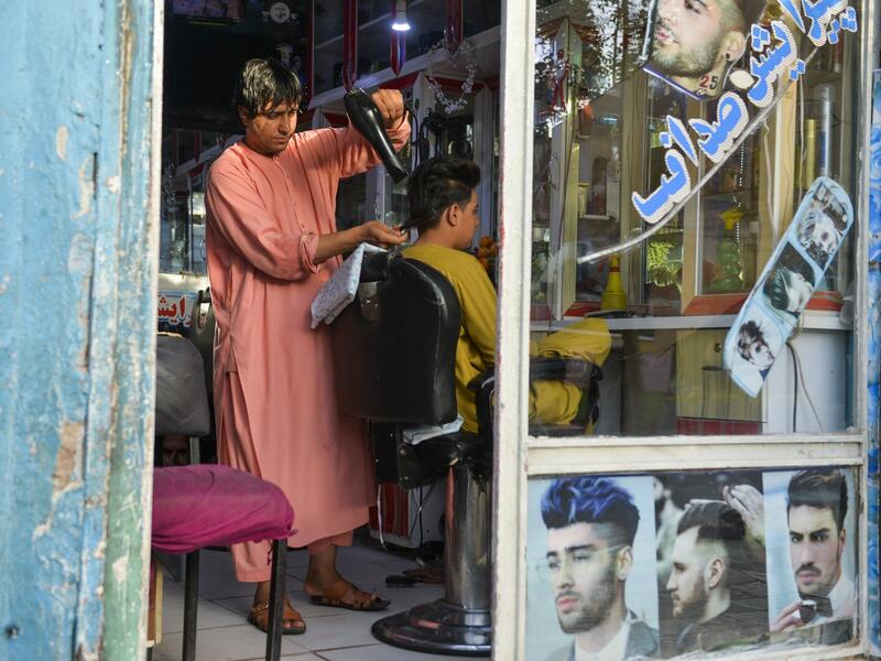 In this picture taken on September 19, 2021, 24-year old Nader Shah attends a customer at his barbershop in Herat. 