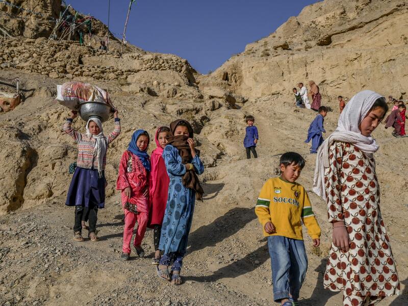 In this picture taken on October 3, 2021, children walk to a river from their village near the cliffs pockmarked by caves where people still live as they did centuries ago in Bamiyan. 