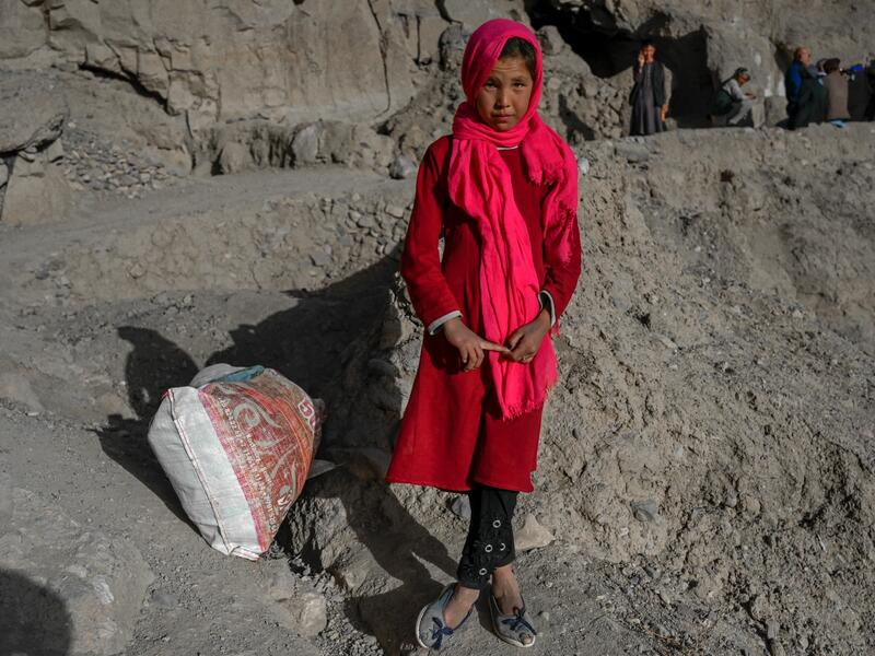 In this picture taken on October 3, 2021, a Hazara ethnic girl stands near a cliff pockmarked by caves where people still live as they did centuries ago in Bamiyan. 
