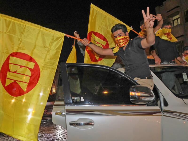 Supporters of the Kurdistan Democratic Party (KDP) celebrate with the KDP party flags during Iraq's parliamentary election in Arbil, the capital of the northern Iraqi Kurdish autonomous region, on October 10, 2021. Preliminary turnout figures showed many citizens boycotted Iraq's parliamentary election, held a year early to appease protestors, in an oil-rich country riddled by corruption and beholden to armed factions. (Photo by SAFIN HAMED / AFP)