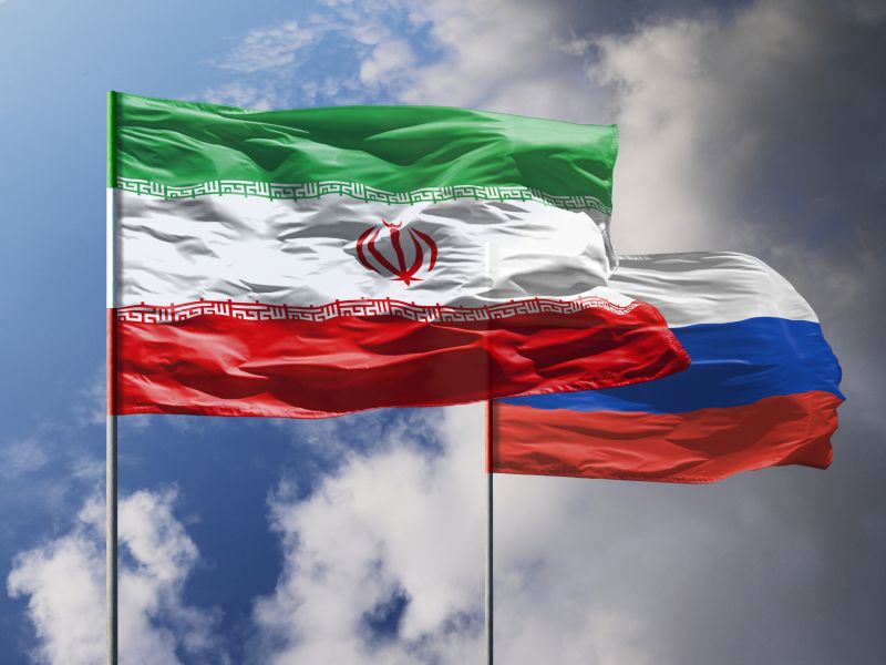 صورة تُظهر أعلام إيران وروسيا مرفوعة على خلفية سماء زرقاء