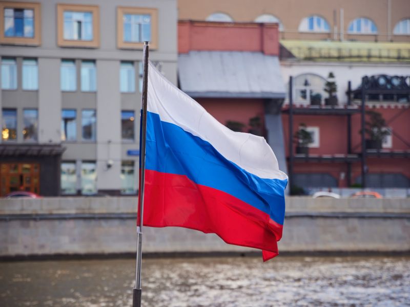 موسكو، روسيا – 6 يونيو 2025: علم روسيا على خلفية مبنى قديم يحمل كتابة "موسكو" باللغة الروسية.