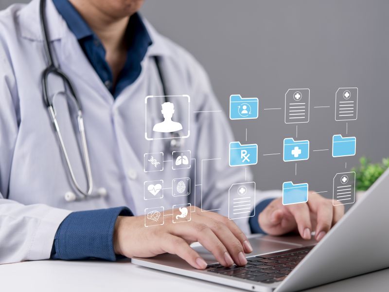 طبيب يستخدم حاسوباً محمولاً مع ظهور رموز رقمية تمثل السجلات الطبية 
