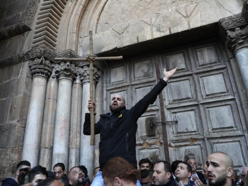 A Palestinian man holds a cross during a protest in front of the Church of the Holy Sepulchre in Jerusalem (AFP/File Photo)