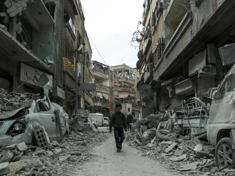 A picture taken on Mar. 8, 2018 shows a Syrian child walking down a street past rubble from destroyed buildings, in the rebel-held town of Douma in the Eastern Ghouta enclave on the outskirts of Damascus.  (HAMZA AL-AJWEH / AFP)