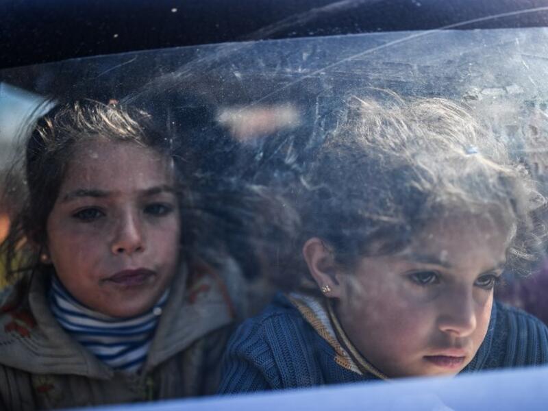 Syrian children look on as they arrive at a check point in the village of Anab ahead of crossing to the Turkish-backed Syrian rebels side on Mar. 17, 2018, as civilians flee the city of Afrin in northern Syria. (BULENT KILIC / AFP)