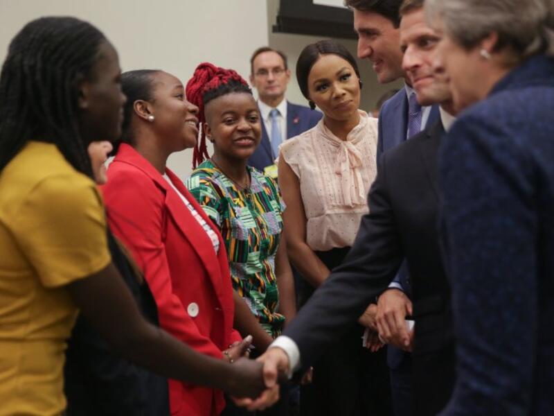 A woman reacts as British Prime Minister Theresa May (L), French President Emmanuel Macron (C) and Canadian Prime Minister Justin Trudeau (R) greet a group of women ahead the start of a Girl Education event at UN headquarters during the General Assembly of the United Nations in New York, September 25, 2018. 
AMR ALFIKY / AFP / POOL