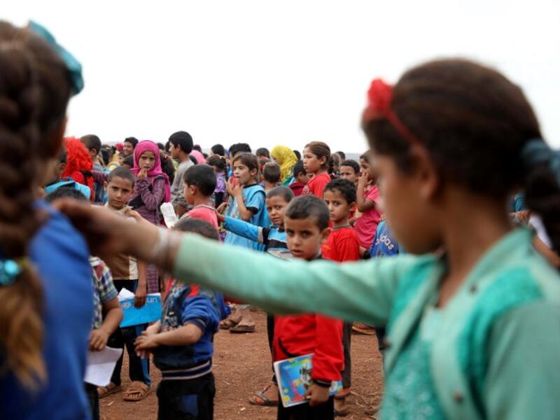 Syrian children who fled with their families from the northern countryside of Hama, line up in the yard of the makeshift school of "Zuhur al-Mustaqbal" (in Arabic "Flowers of the Future") in al-Jeneinah camp for displaced people in the village of Atme, in Syria's mostly rebel-held northern Idlib province, on October 1, 2018. Aaref WATAD / AFP