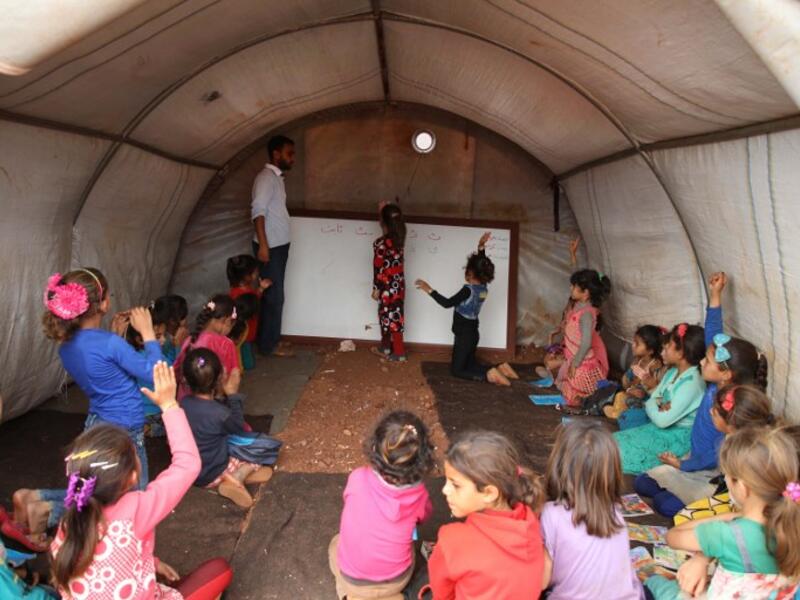 Syrian children who fled with their families from the northern countryside of Hama, attend a class at the makeshift school of "Zuhur al-Mustaqbal" (in Arabic "Flowers of the Future") in al-Jeneinah camp for displaced people in the village of Atme, in Syria's mostly rebel-held northern Idlib province, on October 1, 2018. Aaref WATAD / AFP