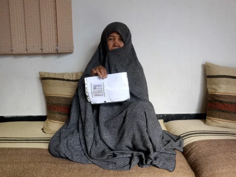 In this photo taken on October 11, 2018. Afghan housewife Fatimah, 55, poses for a picture as she holds her ID card or Tazkira registered to vote in the upcoming parliamentary election, at her House in Mazar-i-Sharif. 
FARSHAD USYAN / AFP