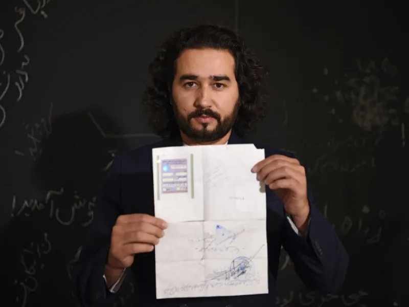 In this photo taken on October 8, 2018, Afghan co-founder and president of ArtLords Omaid Sharifi, 32, poses for a picture as he holds his id card or Tazkira registered to vote in the upcoming parliamentary election, in Kabul. 
WAKIL KOHSAR / AFP