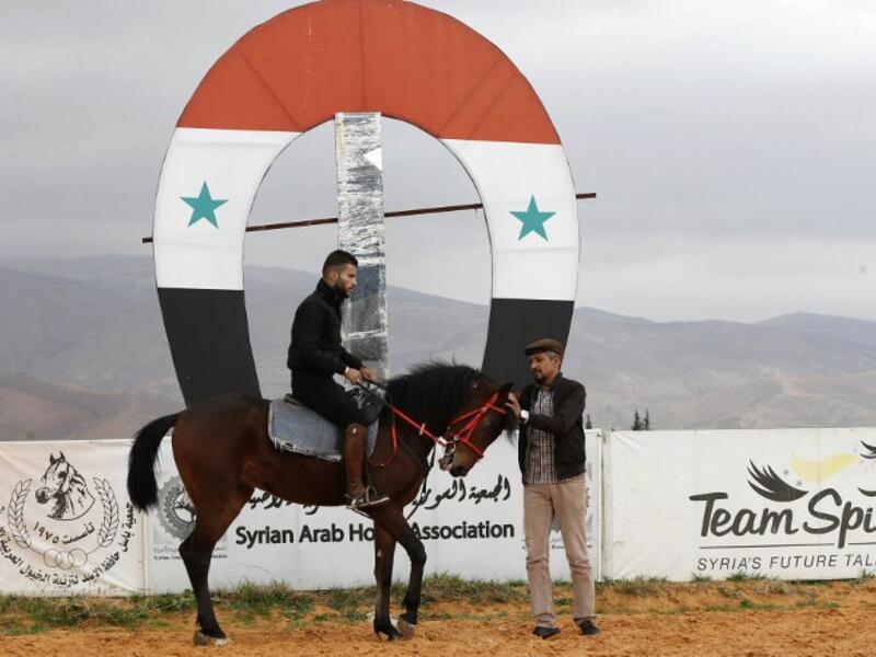 A Syrian man prepares to ride a horse at a track in the town of Dimas, west of the Syrian capital Damascus LOUAI BESHARA / AFP