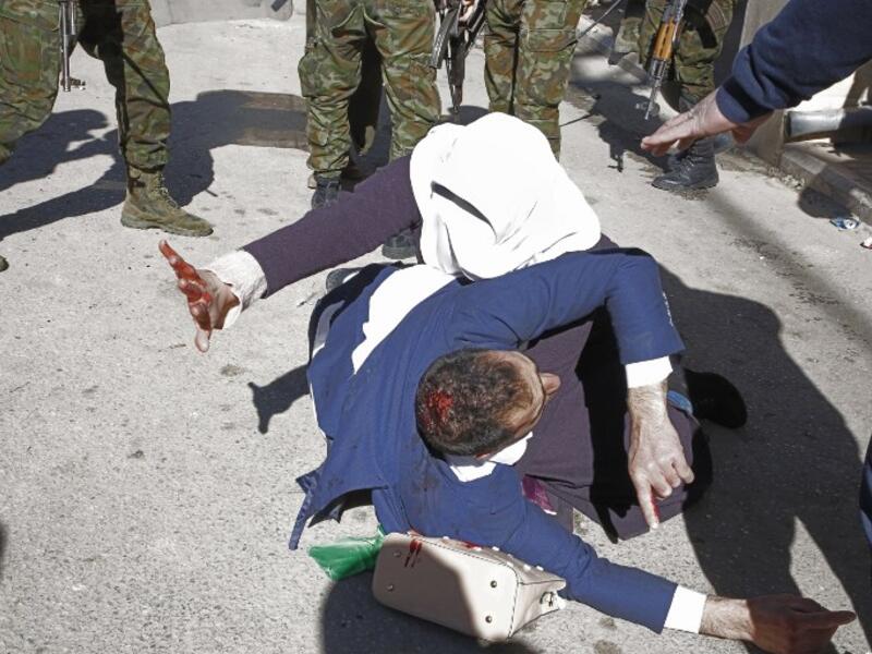 A Palestinian woman shields her injured husband as Palestinian security forces try to disperse a rally of Hamas supporters, marking the 31st anniversary of the founding of the Islamist movement.
HAZEM BADER / AFP