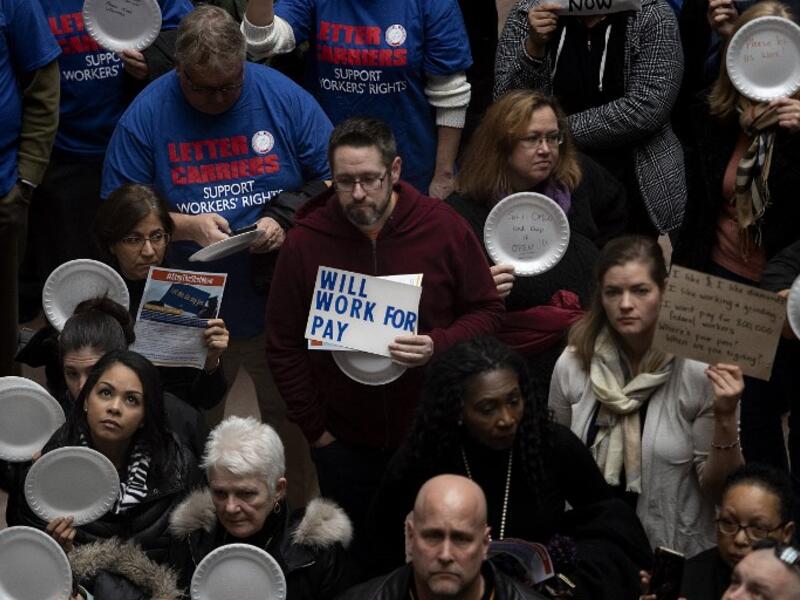 A federal worker stands with a placard reading "Will Work For Pay" as other federal employees stage a rally to call for a vote on the shutdown. (AFP/ File)