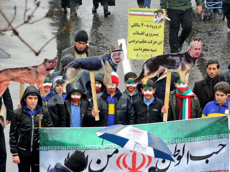 Iranian children, some with face paint in the national flag's colours, pose behind a banner depicting the national flag and with signs depicting dogs with the faces of (L to R) US President Donald Trump, Saudi King Salman bin Abdulaziz, and Israeli Prime Minister Benjamin Netanyahu.
ATTA KENARE / AFP