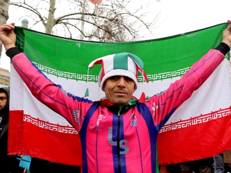 An Iranian man wearing a jester's hat coloured with the national flag's colours poses with a national flag during commemorations of the 40th anniversary of Islamic Revolution in the capital Tehran on February 11, 2019. 
ATTA KENARE / AFP