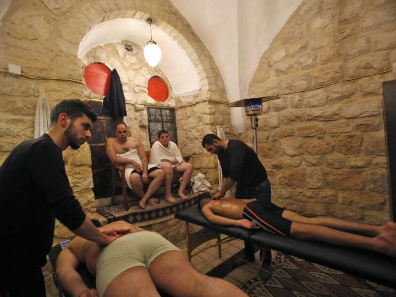 Men wait as others receive massages at the first traditional Turkish bath (Hammam) opening in the occupied Palestinian West Bank city of Hebron on March 11, 2019. 
HAZEM BADER / AFP