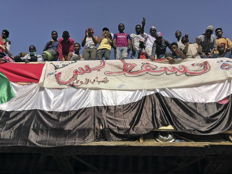 Sudanese men gather atop a pedestrian crossing with a national flag and a banner reading in Arabic "Just fall that is all", during a demonstration in front of the military headquarters in the capital Khartoum on April 9, 2019.
AFP/ File