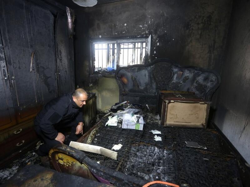 A Palestinian police member inspects the damage inside a burnt-out house belonging to a key witness to an arson attack which took place last year by Jewish extremists that killed a Palestinian family, in the Israeli occupied West Bank village of Duma, after fire broke out in the home in the early hours of March 20, 2016. (AFP/Jaafar Ashtiyeh)