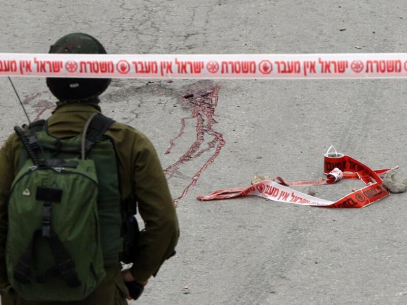 Blood stains from the body of a Palestinian assailant who was allegedly shot in the head by an Israeli soldier as he lay wounded on the ground after injuring an Israeli soldier with a fellow Palestinian attacker in a stabbing assault, stain the ground on March 24, 2016. (AFP/Hazem Bader)