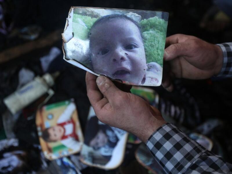 A man shows a picture of 18-month-old Palestinian toddler Ali Saad Dawabsha who died when his family house was set on fire by alleged Jewish extremists in the West Bank village of Duma on July 31, 2015. (AFP/Jaafar Ashtiyeh)