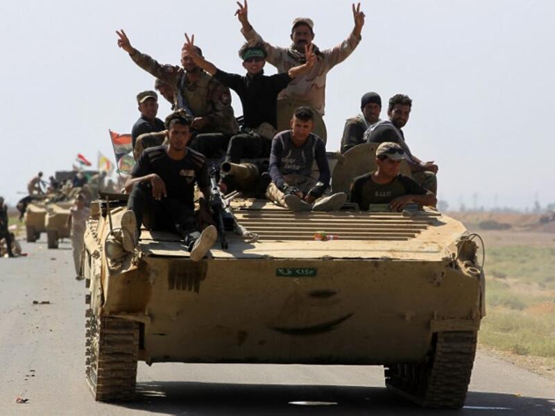Members of the Hashed al-Shaabi (Popular Mobilization) paramilitaries flash the victory gesture as they ride atop an infantry-fighting vehicle during the advance towards villages between the northern Iraqi cities of Hawija and Kirkuk on October 6, 2017
AHMAD AL-RUBAYE / AFP