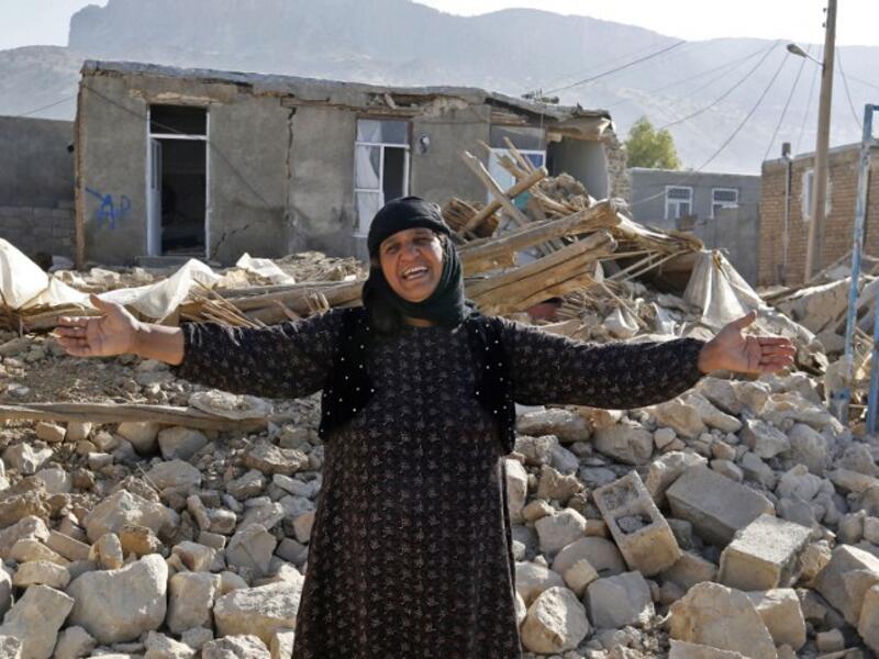 An Iranian woman gestures next to the rubble of her home in Kouik village.

(ATTA KENARE / AFP) 