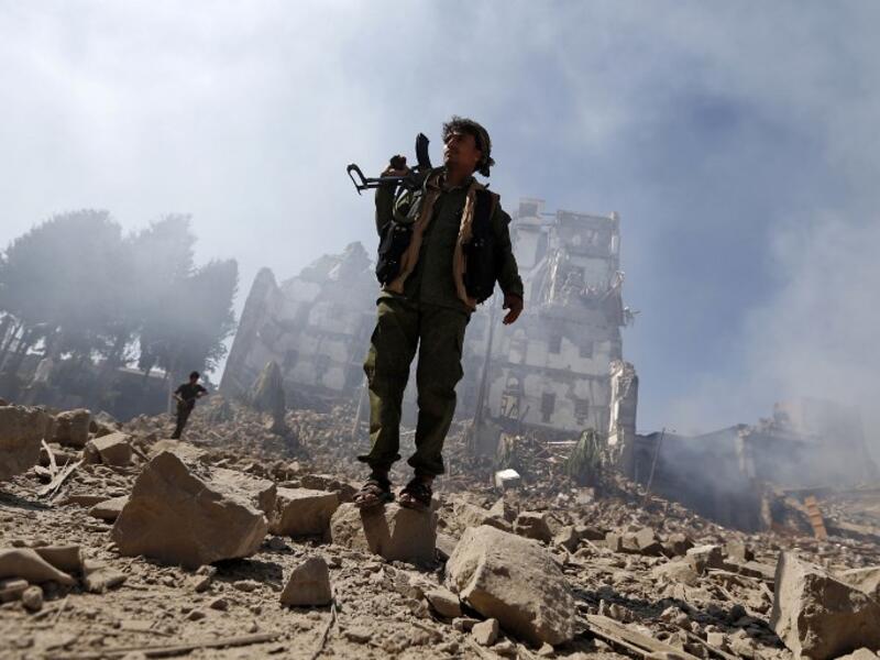 Houthi rebel fighters inspect the damage after a reported air strike carried out by the Saudi-led coalition targeted the presidential palace in the Yemeni capital Sanaa on Dec. 5, 2017. (Mohammed HUWAIS / AFP)
