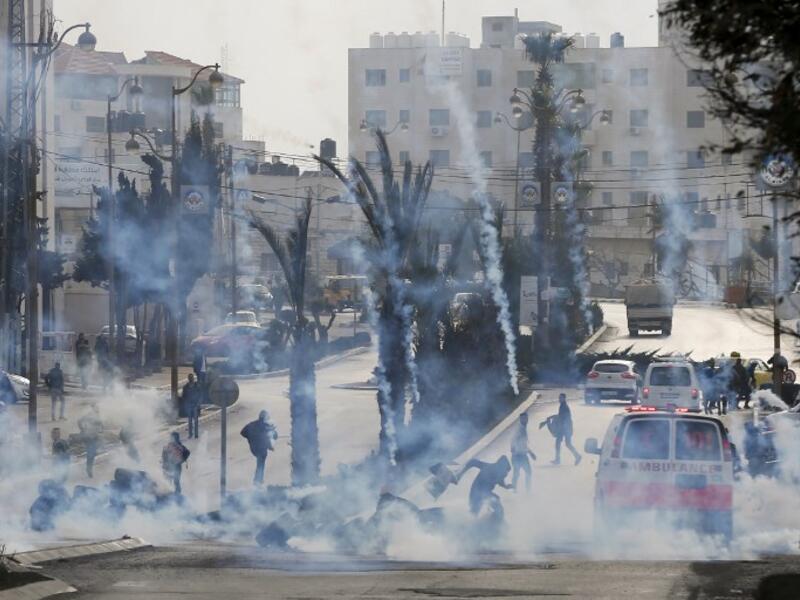 Palestinian protesters take cover from tear gas during clashes with Israeli forces on Jan. 12, 2018 north of Ramallah in the Israeli-occupied West Bank. 
ABBAS MOMANI / AFP