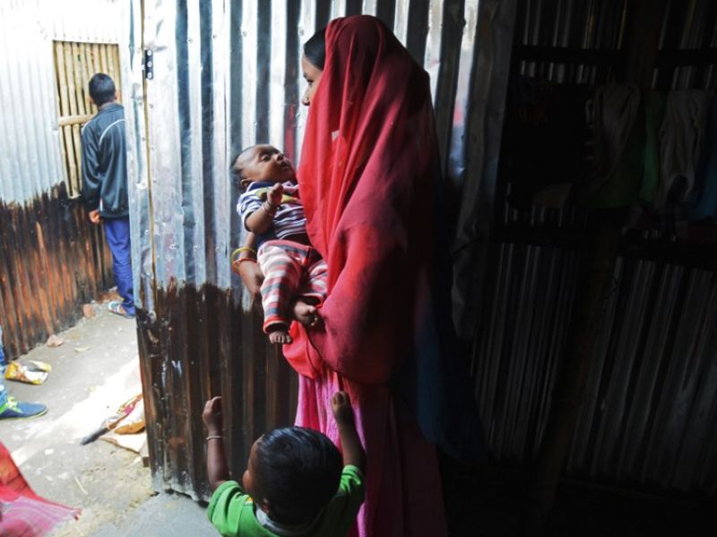 A Rohingya refugee carrying a baby stands at a temporary shelter near the village of Baruipur, some 55km south of Kolkata on Jan. 19, 2018 (Dibyangshu SARKAR / AFP)