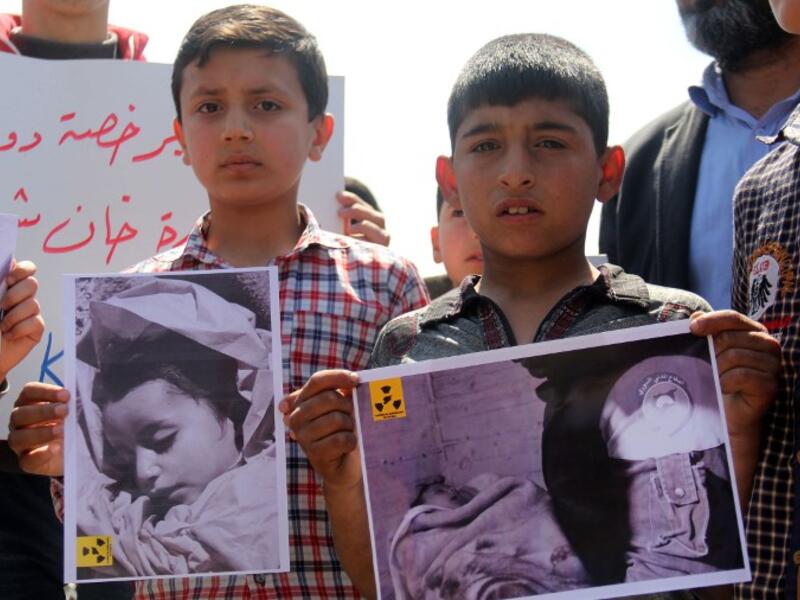 In this file photo taken on April 7, 2017, Syrian residents of Khan Sheikhun hold placards and pictures during a protest condemning a suspected chemical weapons attack on the town that killed at least 86 people (Omar haj kadour / AFP)