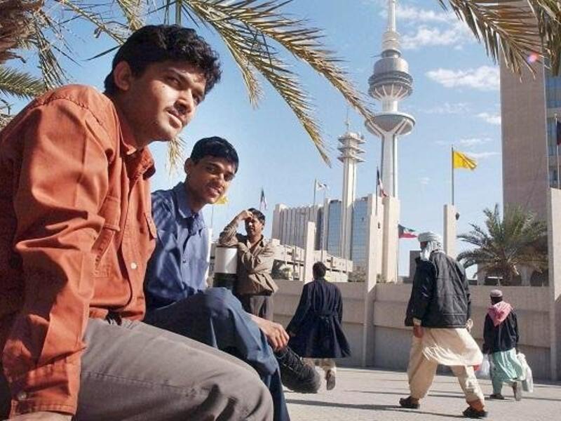 Asian workers take a break after work at a park next to Kuwait's Liberation Tower (AFP/File Photo)