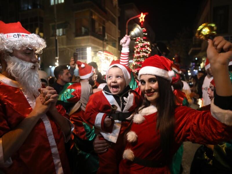 Syrian people dressed as Santa Claus walk in the capital Damascus' central neighbourhood of Qassaa to celebrate Christmas early on December 22, 2018. 
LOUAI BESHARA / AFP