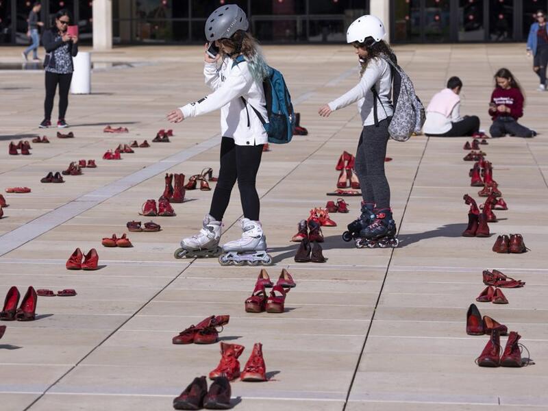 Israelis walk past an installation of red shoes during a rally against domestic violence in the Israeli coastal city of Tel Aviv on December 4, 2018 (Twitter)