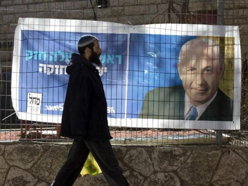 An Israeli settler walks past campaign posters of Israeli Prime Minister Binyamin Netanyahu at the Kiryat Arba settlement, in the Israeli occupied West Bank. (AFP PHOTO/MENAHEM KAHANA)